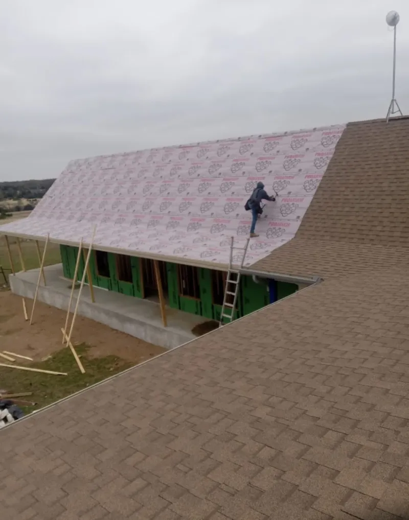 Worker preparing underlayment for a metal roof installation in Marlboro